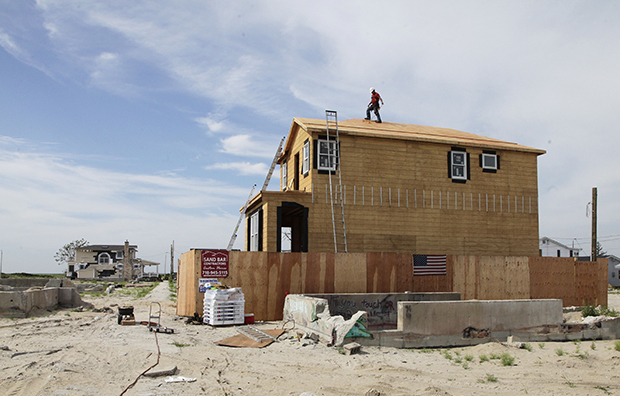 A worker walks the roof line of a house under construction in the Breezy Point community of New York's Queens borough on Wednesday, July 24, 2013. It is the first house to be rebuilt in the beachfront community, where more than 110 homes burned to the ground during Superstorm Sandy in October 2012. (AP/Mark Lennihan)