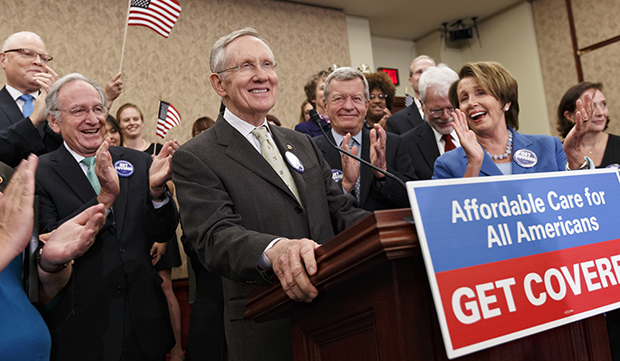 Senate Majority Leader Harry Reid (D-NV), center, accompanied by other lawmakers and people whose lives have been impacted by lack of health insurance, smiles during a news conference on Capitol Hill in Washington, Tuesday, October 1, 2013. (AP/J. Scott Applewhite)
