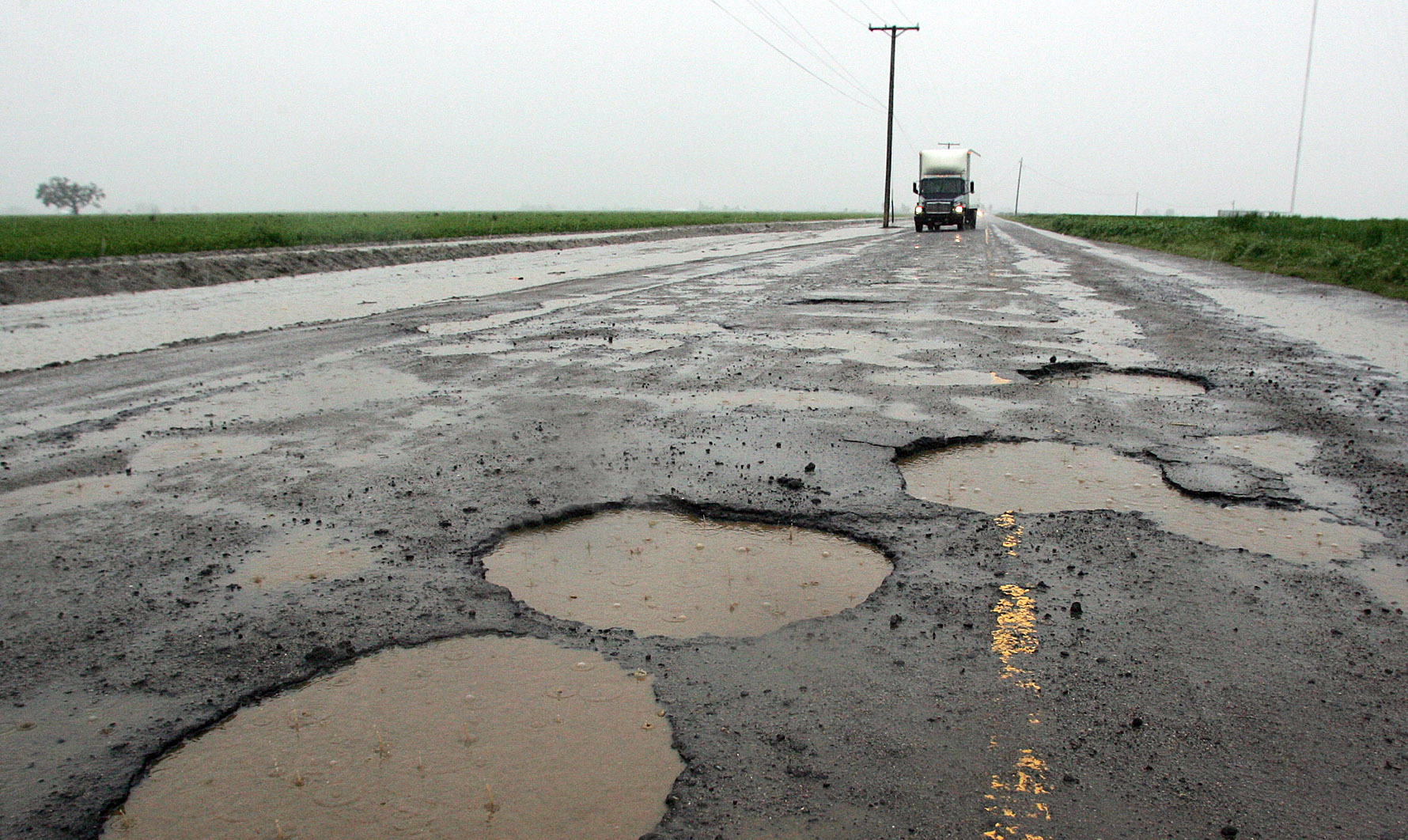 Potholes are visible on a farming back road in Tulare, California. (AP/Gary Kazanjian)