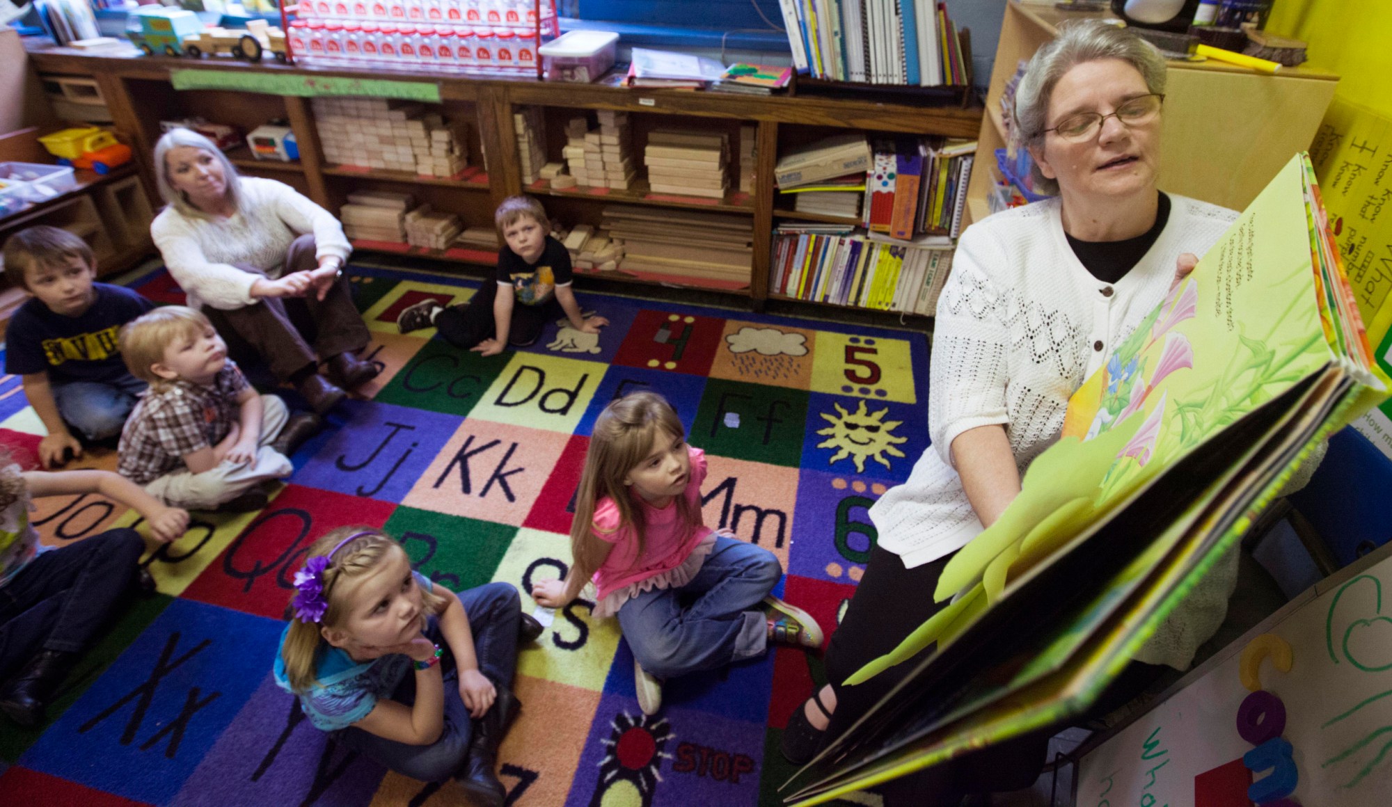Early Childhood Coordinator Jacki Wimmer reads to pre-K students at Iaeger Elementary School in West Virginia. Early childhood education is one program that could be supported using social finance mechanisms. (AP/Randy Snyder)