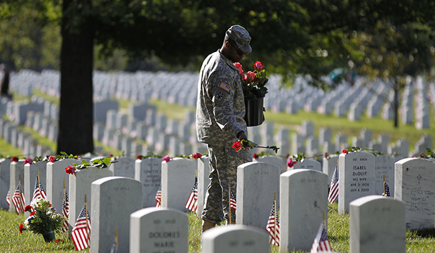 A soldier places roses on grave stones at Arlington National Cemetery in Arlington, Virginia. (AP/Molly Riley)
