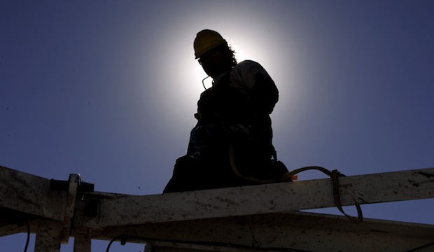 A worker is silhouetted by the sun as he helps dismantle an oil rig to move it to a new drilling site at a site near Elk City, Oklahoma. (AP)