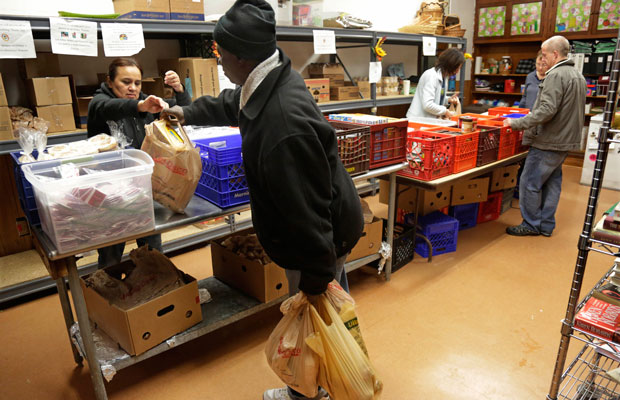 Volunteers at St. Ignatius Food Pantry bag items for individuals and families as a temporary increase in food stamp dollars from the 2009 economic stimulus expires, and more than 2 million low-income Illinois residents benefits are cut. (AP/M. Spencer Green)