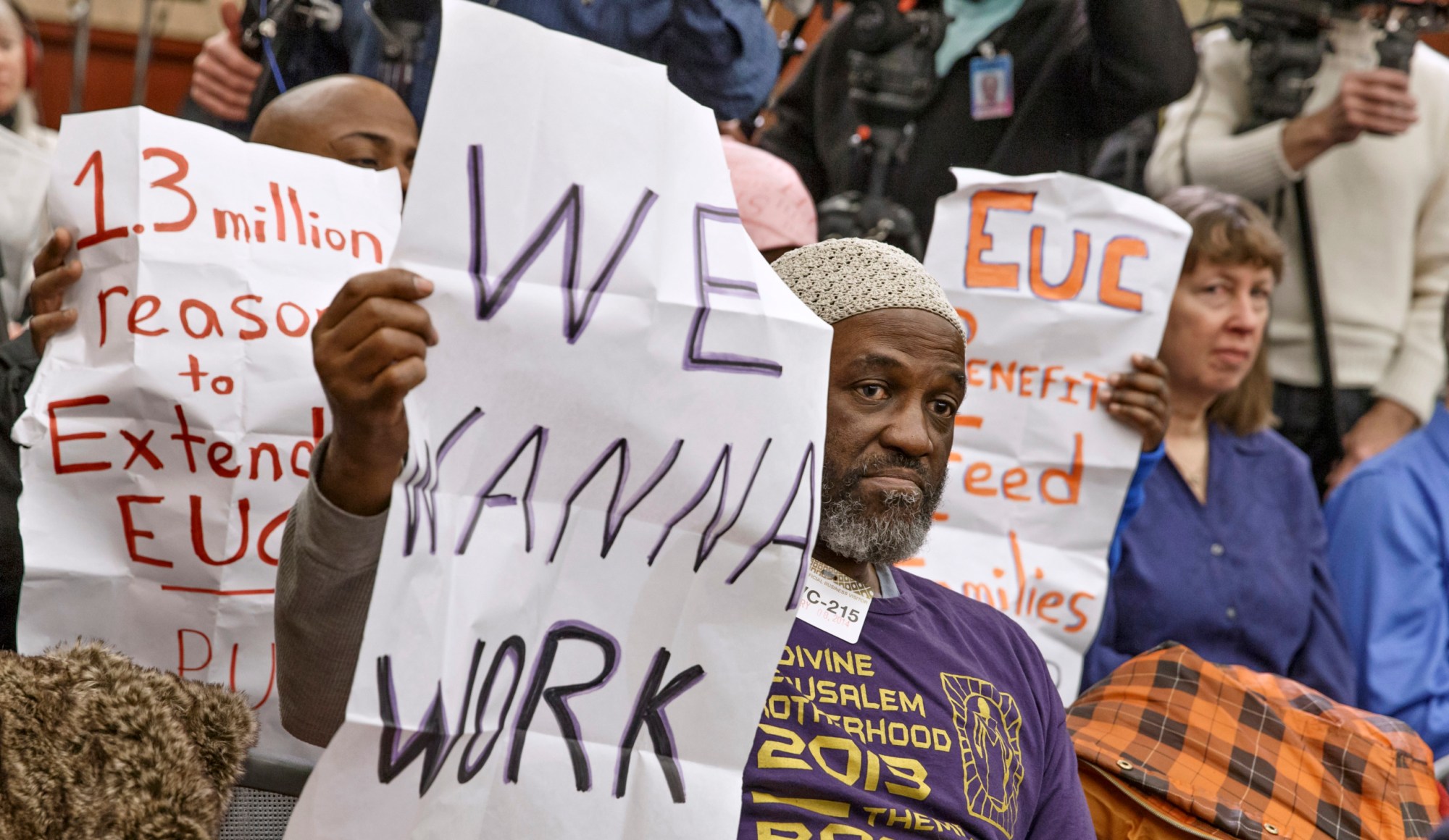 Audience members hold signs appealing for jobs at a news conference about extending unemployment insurance benefits. (AP/J. Scott Applewhite)