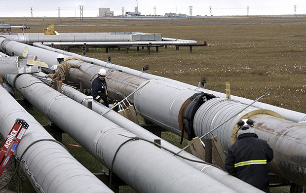 BP workers, in the background, remove insulation from an oil transit pipeline at the Prudhoe Bay oil field on Alaska's North Slope, August 18, 2006, as other workers use ultrasound to test for weakness in the pipe due to corrosion. (AP/Al Grillo)