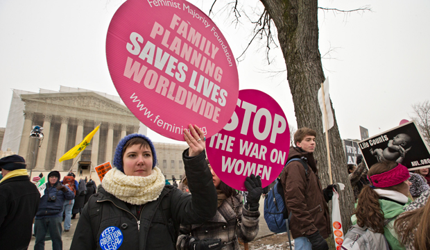 Abortion rights protesters hold signs as anti-abortion activists march past the Capitol to the Supreme Court in Washington, Friday, January 25, 2013, as they observe the 40th anniversary of the Roe v. Wade decision. (AP/J. Scott Applewhite)