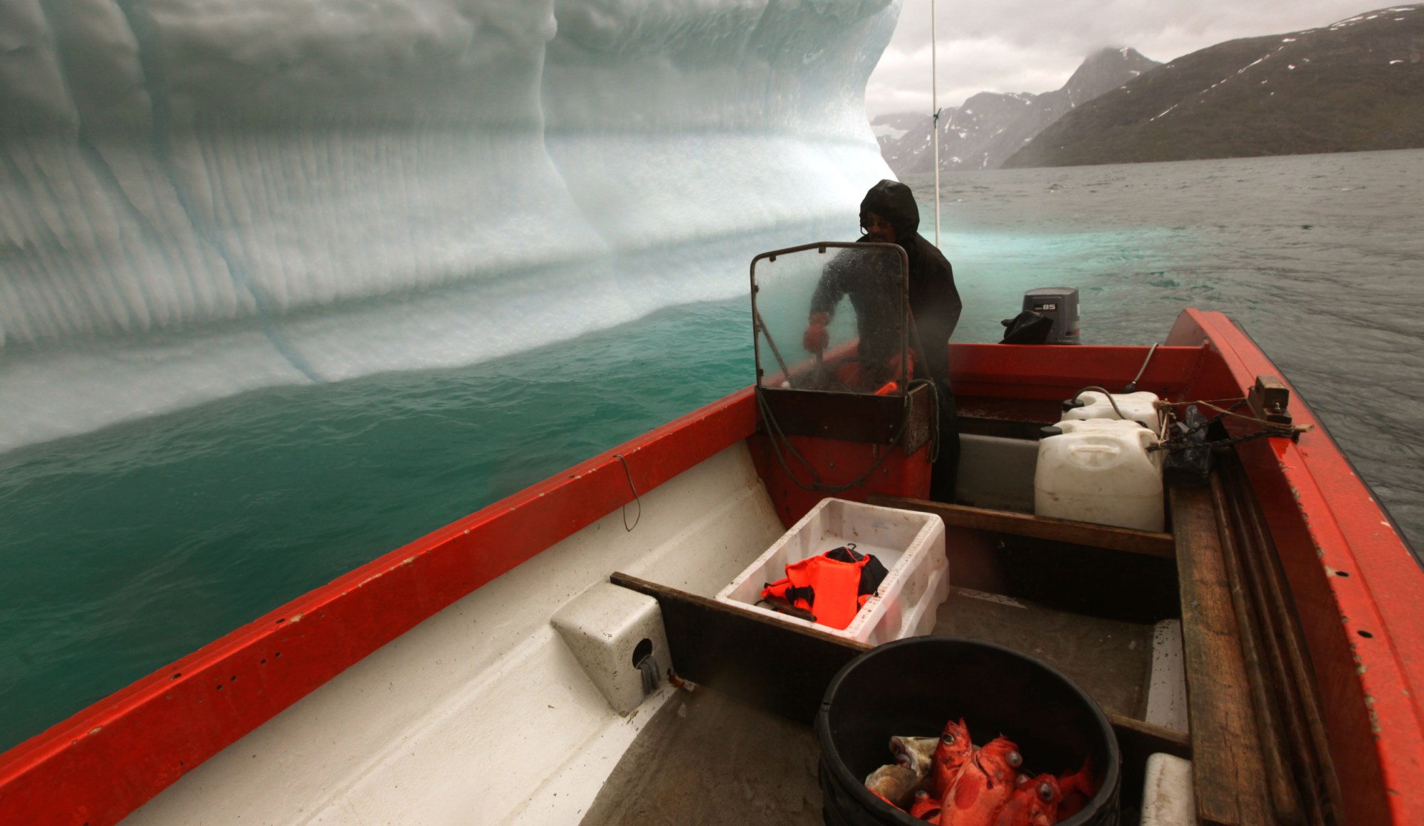 An Inuit hunter and fisherman steers his boat past a melting iceberg and along a fjord leading away from the edge of the Greenland Ice Sheet. (AP/Brennan Linsley)