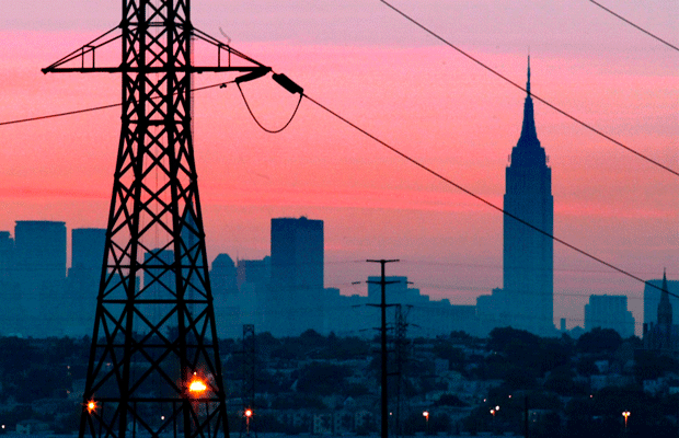 A darkened New York City is visible just before dawn through power lines from Jersey City, New Jersey. (AP/George Widman)