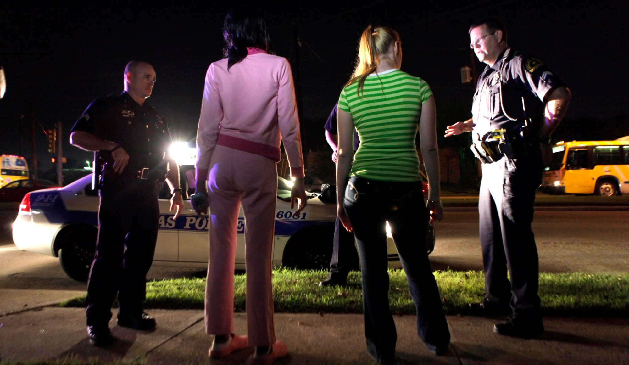 Police talk to two young women before arresting them for prostitution in Dallas. One of the women was underage at the time of her arrest. (AP/LM Otero)