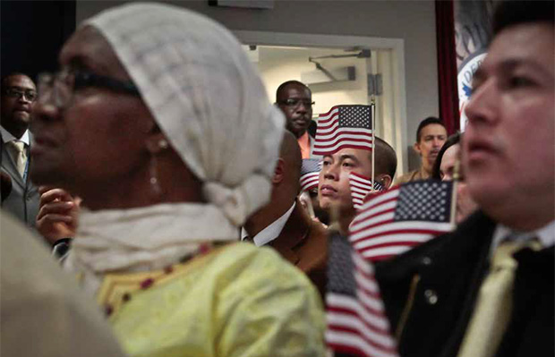 Inmigrantes con banderas miniaturas de los EEUU escuchando al Presidente Barack Obama durante una ceremonia de ciudadania en NY el 18 de diciembre del 2013 (AP/Bebeto Matthews)