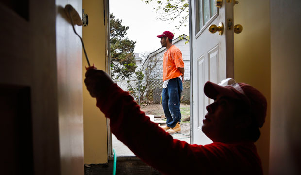 Victoriano Del La Cruz, a carpenter from Mexico, stands just outside of a basement entrance as Sergio Ajche from Guatemala finishes a painting job in New York. (AP/Bebeto Matthews)