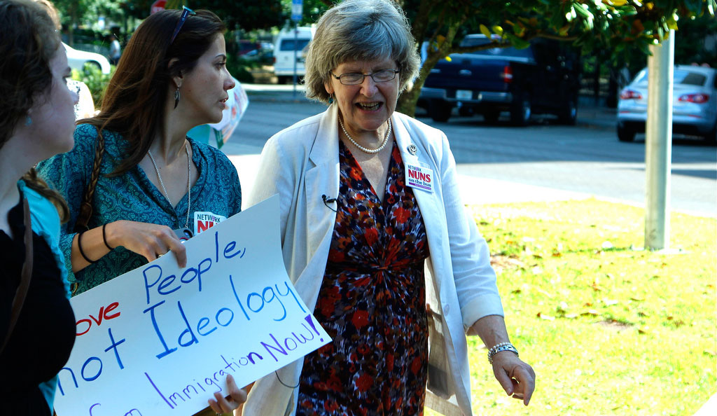Sister Simone Campbell walks with a demonstrator. (Flickr/reptilelingerie)