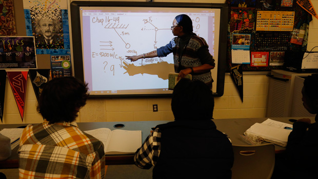 A teacher works with students in an Advanced Placement physics class, February 7, 2014. (AP/Charles Dharapak)