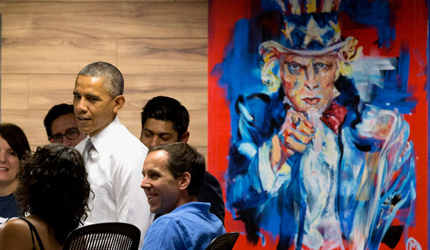 President Barack Obama stands next to a painting of