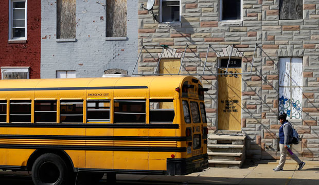 A student walks past vacant row houses to a waiting school bus as school gets out for the day in Baltimore. (AP/Patrick Semansky)