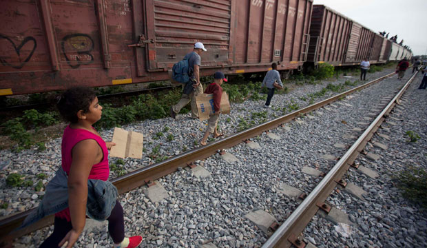 Migrants walk along the rail tracks after getting off a train during their journey toward the U.S.-Mexico border in Ixtepec, Mexico. (AP/Eduardo Verdugo)
