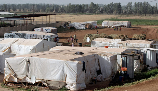 Syrian refugees walk outside their tents at a refugee camp in the eastern Lebanese town of Majdal Anjar, June 2014. (AP/Bilal Hussein)