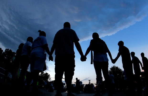 People stand in prayer after marching about a mile to the police station to protest the shooting of Michael Brown in Ferguson, Missouri. (AP/Charlie Riedel)