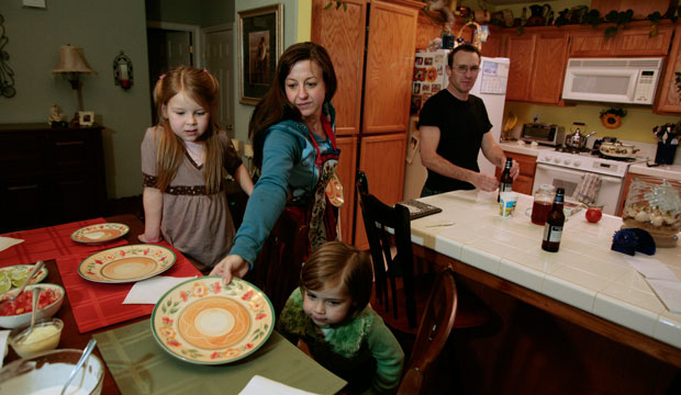 Cindy Reilly, center, sets the dinner table for her children Isabella, 7, left, Sierra, 4, and her husband Mike in the kitchen of their home in Nipomo, California. (AP/Eric Parsons)