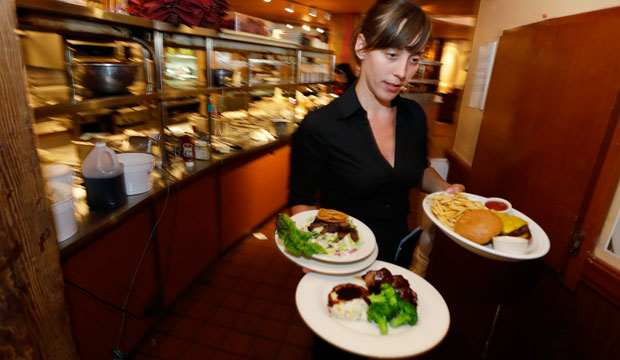 Wendy Harrison, a waitress at the Icon Grill in Seattle, carries food to a table as she works during lunchtime. (AP/Ted S. Warren)
