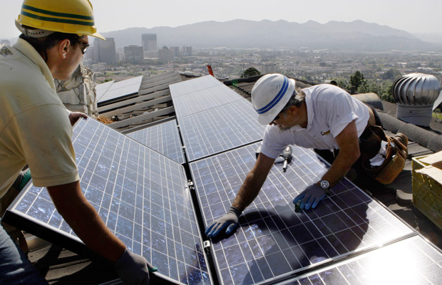 Edward Boghosian and Patrick Aziz, both employees of California Green Design, install solar electrical panels on the roof of a home in Glendale, California. (AP/Reed Saxon)