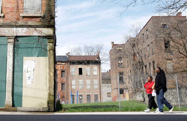 A couple walks past empty, boarded-up buildings in the Over-the-Rhine neighborhood of Cincinnati, Ohio. (AP/Al Behrman)