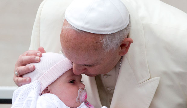 Pope Francis kisses a child as he arrives for his weekly general audience in St. Peter's Square at the Vatican, September 2014. (AP/Alessandra Tarantino)