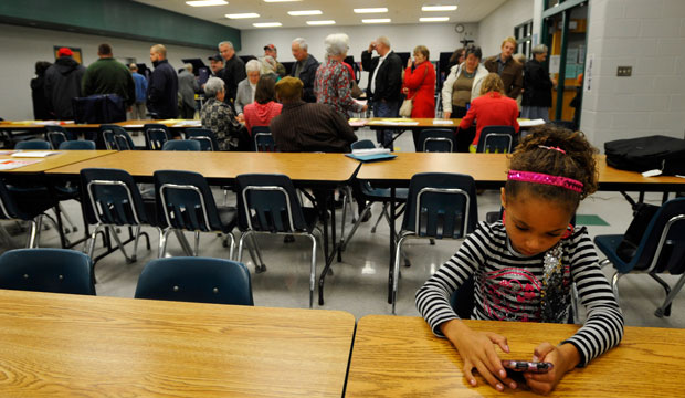 Destiny Davis plays a game on a cell phone as she waits for her mother to vote at Slater-Marietta Elementary School on Election Day, November 2012. (AP/Rainier Ehrhardt)