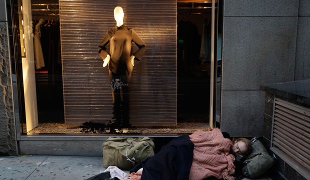 A homeless man sleeps on the sidewalk under a holiday window at Blanc de Chine in New York. (AP/Mark Lennihan)