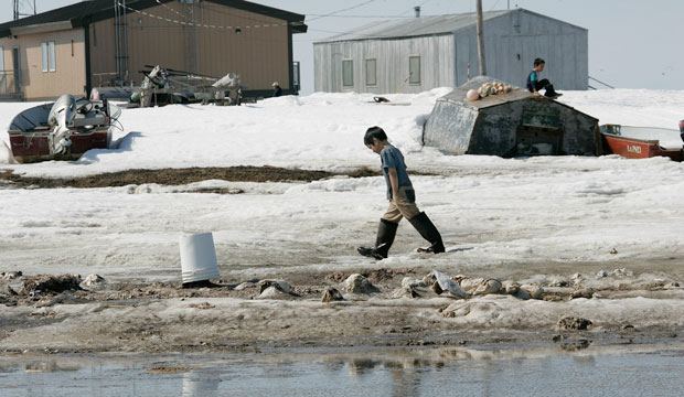 A boy walks along the banks of the Newtok River in the village of Newtok, Alaska. (AP/Al Grillo)