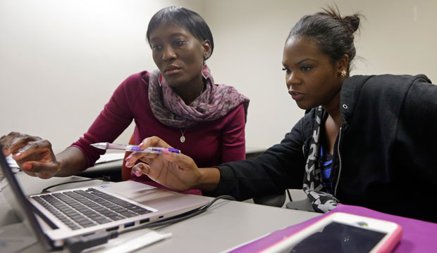 Certified Marketplace Navigator Nathalie Milias, left, helps Miami Dade College student Alicha Theodore, right, choose a health plan after Theodore signed up for health insurance. (AP/Alan Diaz)