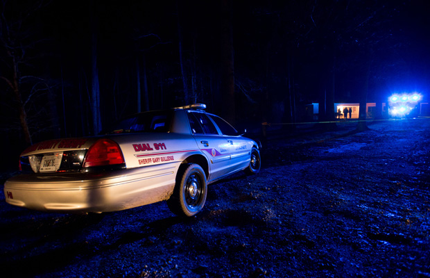 A police officer's car is parked outside a home where a shooting took place. (AP/Kevin Liles)