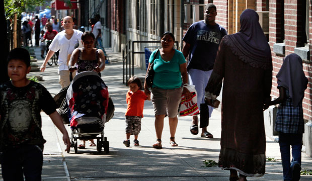 Pedestrians walk along 144th Street between 7th Avenue and Frederick Douglas Boulevard in Harlem, New York, on June 28, 2011. (AP/Bebeto Matthews)