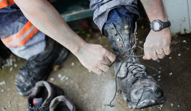 Third-generation coal miner Keith Johnson takes off his boots after working the graveyard shift in a coal mine in Evarts, Kentucky. (AP/David Goldman)