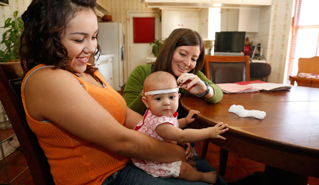 Sara Young, right, measures Sophia Payne, center, held by her mother, Cristina Swank, during a home visit in Oklahoma City. (AP/Sue Ogrocki)