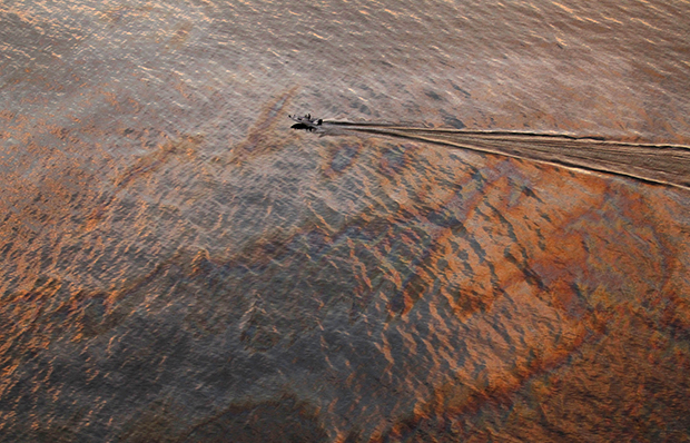 At sunset, a boat motors through oil sheen from the Deepwater Horizon oil spill off East Grand Terre Island, where the Gulf of Mexico meets Barataria Bay, on the Louisiana coast, July 31, 2010. (AP/Gerald Herbert)