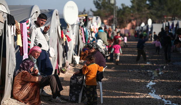 Syrian refugees who fled violence in Kobani are seen outside their tents in a camp in Suruc, Turkey. (AP/Emrah Gurel)