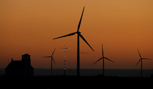 Wind turbines from the Smoky Hills Wind Farm dwarf the Excelsior Lutheran Church at dusk on Friday, December 5, 2014, near Wilson, Kansas. (AP/Charlie Riedel)