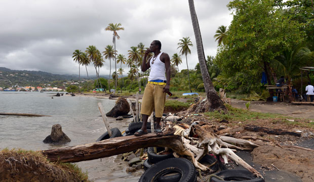 Fisherman Desmond Augustin stands on a breakwater of old tires and driftwood that local residents fashioned to try and protect their fishing village in Telegraph, Grenada. (AP/David McFadden)