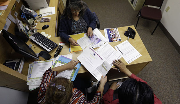 Case manager Rosario Mezo, top, helps immigrants with documents pertaining to their U.S.-born daughter at the immigration and legal services of Catholic Charities in Dallas, November 20, 2014. (AP/LM Otero)