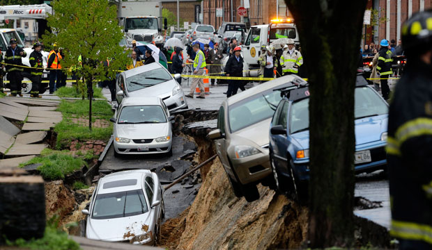 Cars sit on the edge of a sinkhole in the Charles Village neighborhood of Baltimore, April 30, 2014, as heavy rain moved through the region. (AP)