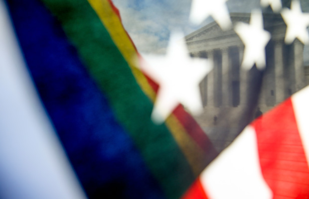A rainbow colored flag, seen through an American flag, flies in front of the Supreme Court in Washington. (AP/Andrew Harnik)