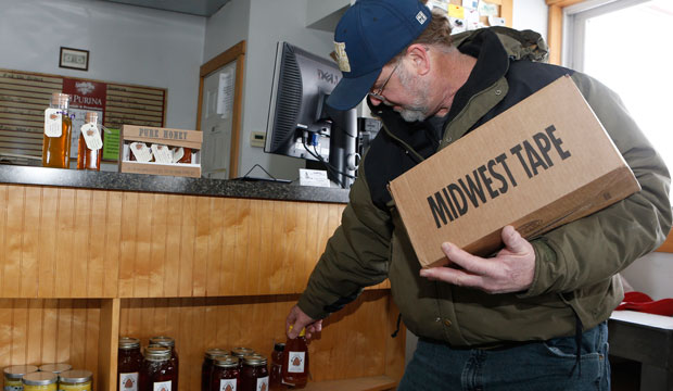 Wayne Wilkin, owner of Wilkin's Backyard Bees, restocks honey at Bucley Bros. Inc. in Wilmington, Ohio. (AP/Gary Landers)