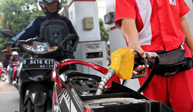 An attendant fills up the tank of a motorbike at a gas station in Jakarta, Indonesia, in September 2014. (AP/Tatan Syuflana)