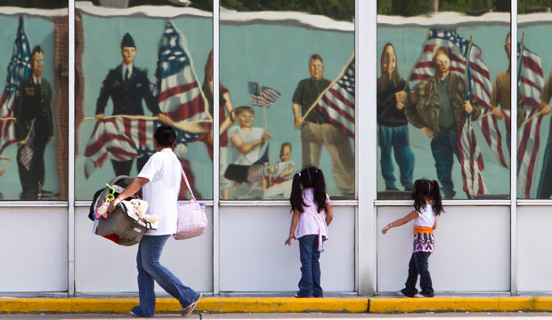 A Hispanic family walks past a reflection of a patriotic mural in Fremont, Nebraska, on July 21, 2010. (AP/Nati Harnik)