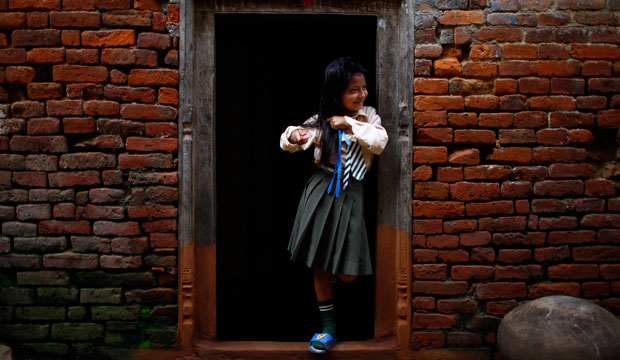 A Nepalese girl gets ready for school as she stands on the entrance to her house in Khokana, on the outskirts of Katmandu, Nepal, in August 2012. (AP/Niranjan Shrestha)