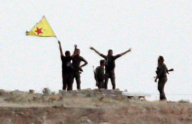 Kurdish fighters from the Kurdish People's Protection Units wave their yellow triangular flag in the outskirts of Tal Abyad, Syria. (AP/Lefteris Pitarakis)