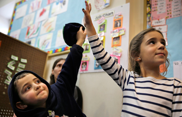 Students raise their hands in their prekindergarten class in Brooklyn, New York, March 11, 2015. (AP/Seth Wenig)