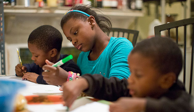 A girl helps her brothers with a drawing and homework in Philadelphia, October 8, 2013. (AP/Matt Rourke)