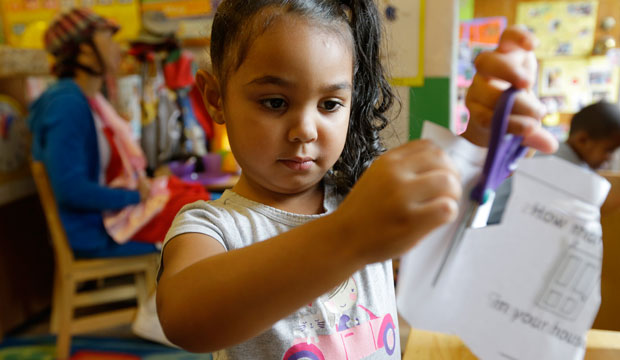 Isis Morton works with scissors and paper in a pre-kindergarten class at the Community Day Center for Children in Seattle, Washington, on October 21, 2014. (AP/Ted S. Warren)